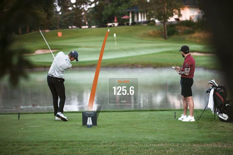 Golfeur utilisant un radar TrackMan pour analyser la vitesse et la trajectoire de la balle après un swing.