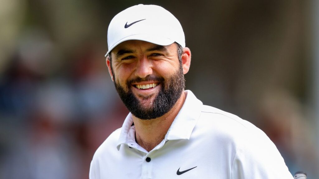 Scottie Scheffler souriant pendant un tournoi de golf, casquette blanche Nike.