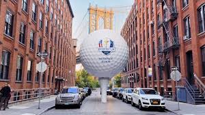 Balle de golf géante Ryder Cup 2025 installée dans une rue de New York avec le pont de Brooklyn en arrière-plan.