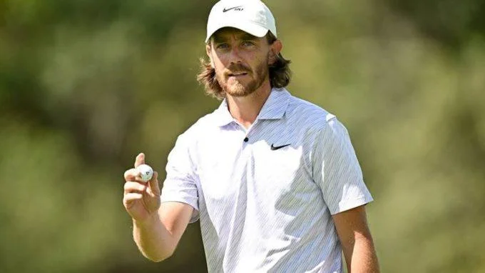 Tommy Fleetwood sur le parcours, tenant une balle de golf après un coup réussi.