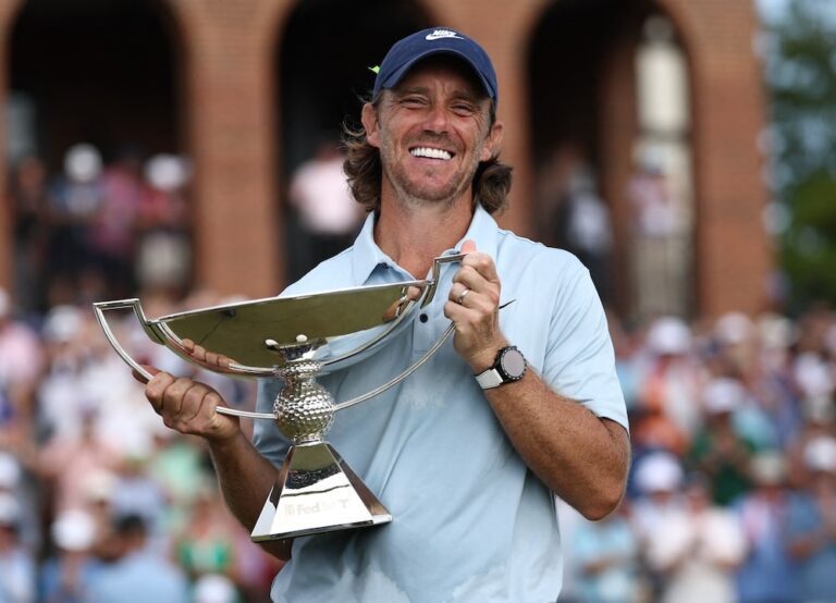 Tommy Fleetwood souriant brandit le trophée de la FedEx Cup 2025.